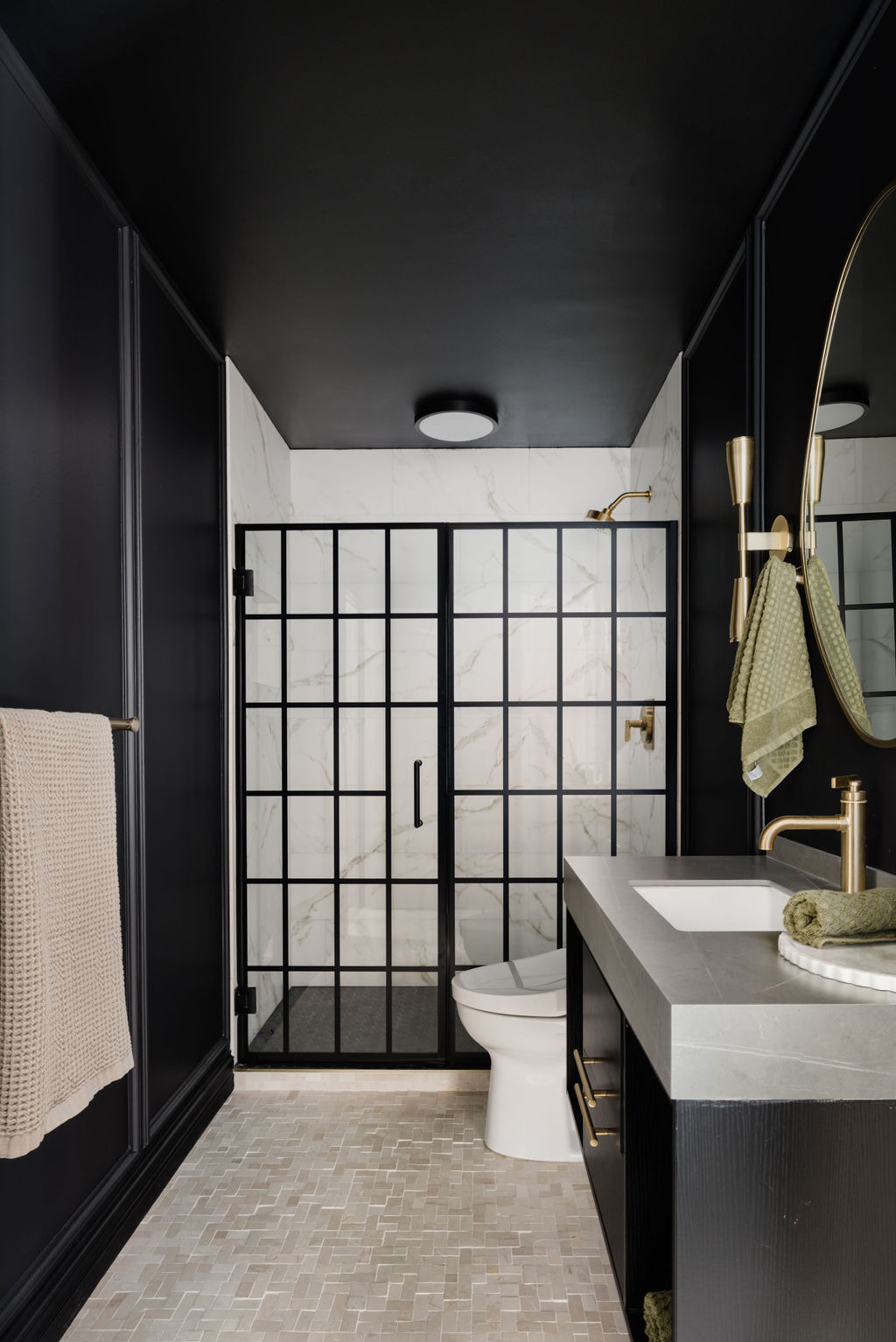 A bathroom with muted mosaic flooring, with walls painted black
