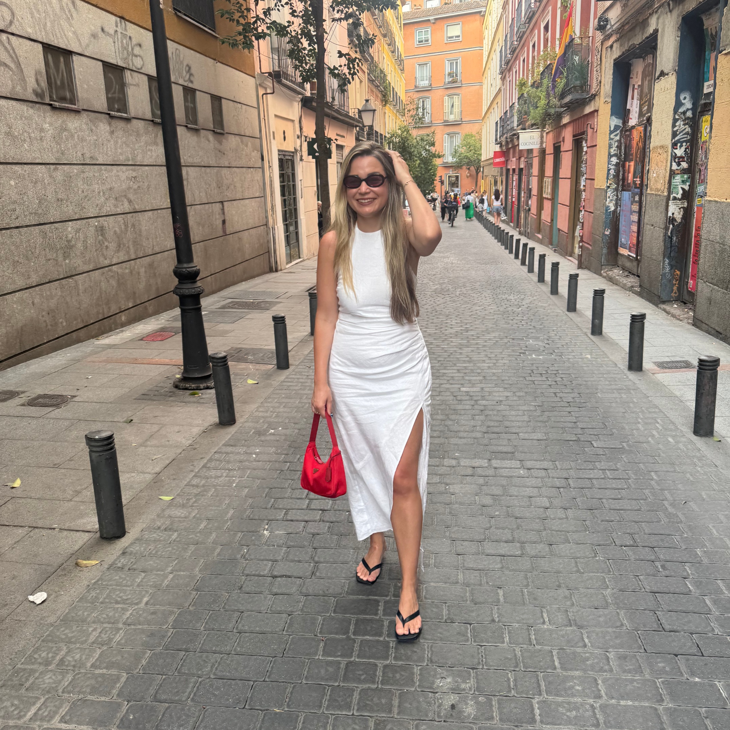 Irina Grechko wearing white dress carrying small red prada bag