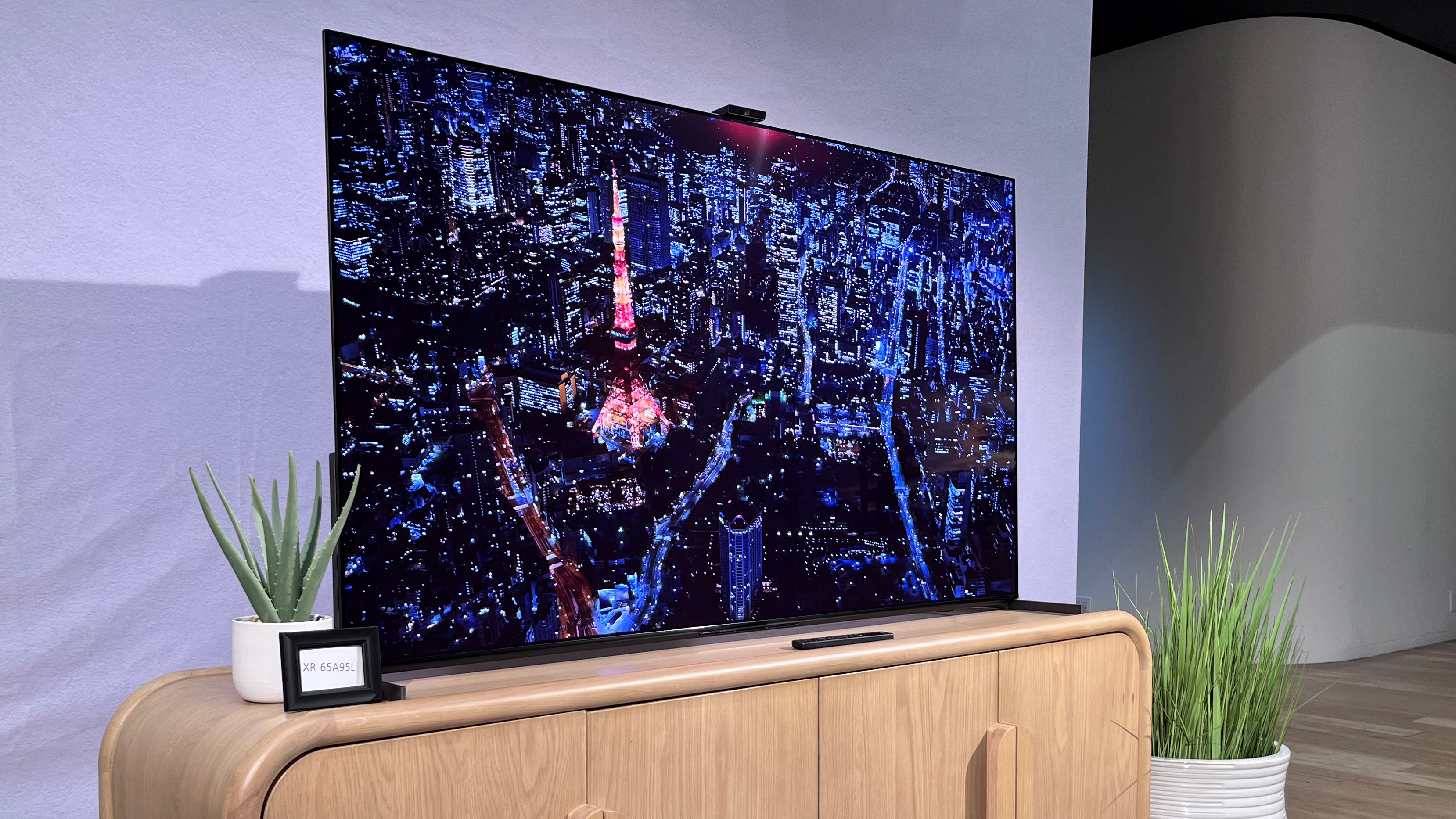 Sony-A95L QD-OLED TV on TV stand shown from side angle with city image onscreen
