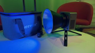 Neewer HB80C video light on a table next to its branded protective case