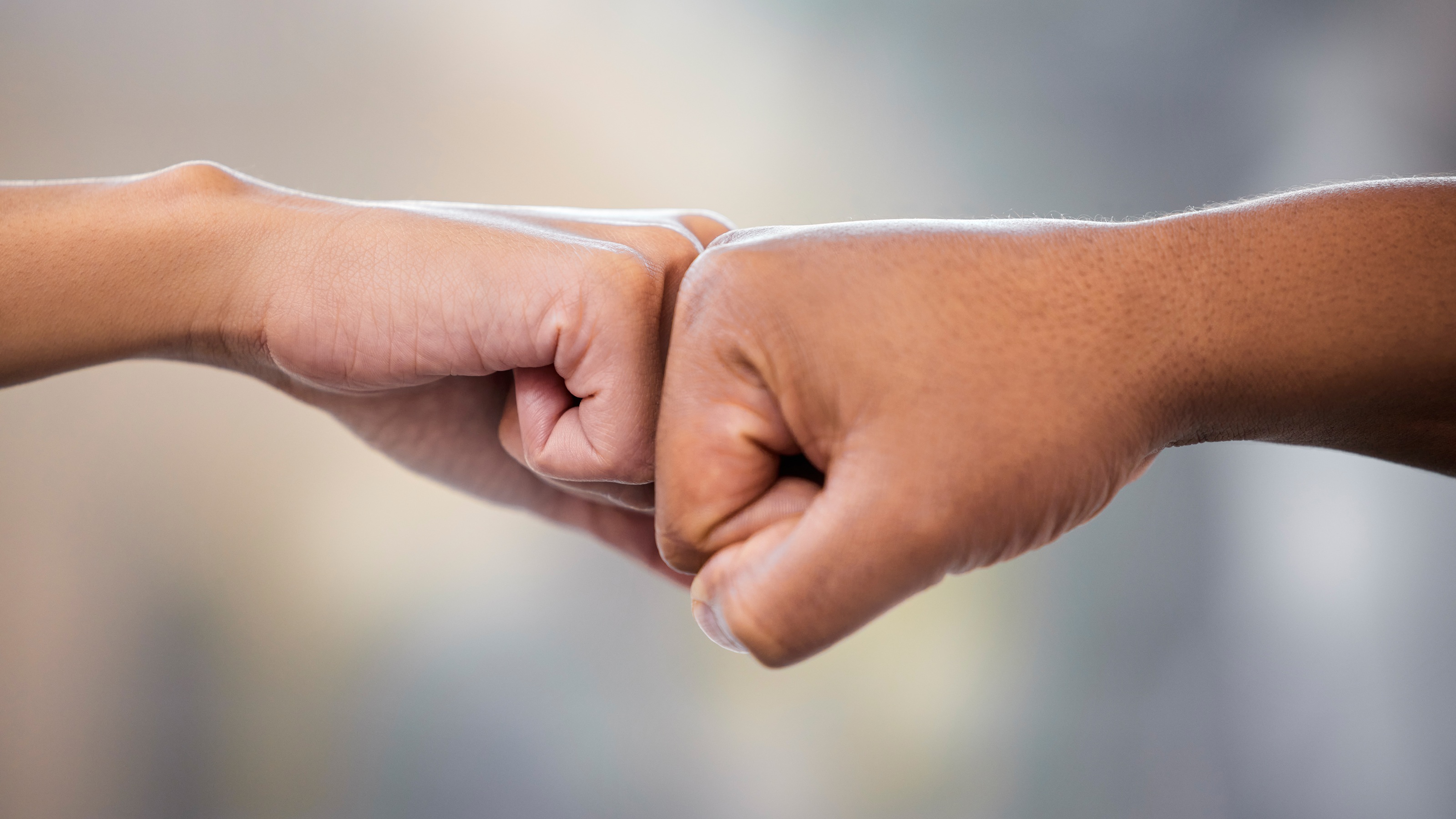 A man and woman fist-bump, only their hands showing.