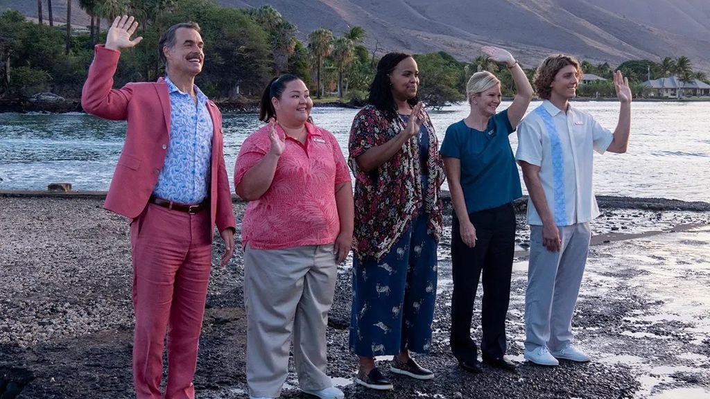 The cast of The White Lotus TV series wave someone off as they stand on a beach