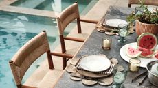 Table setting with neutral tableware, watermelons and a pool in the background