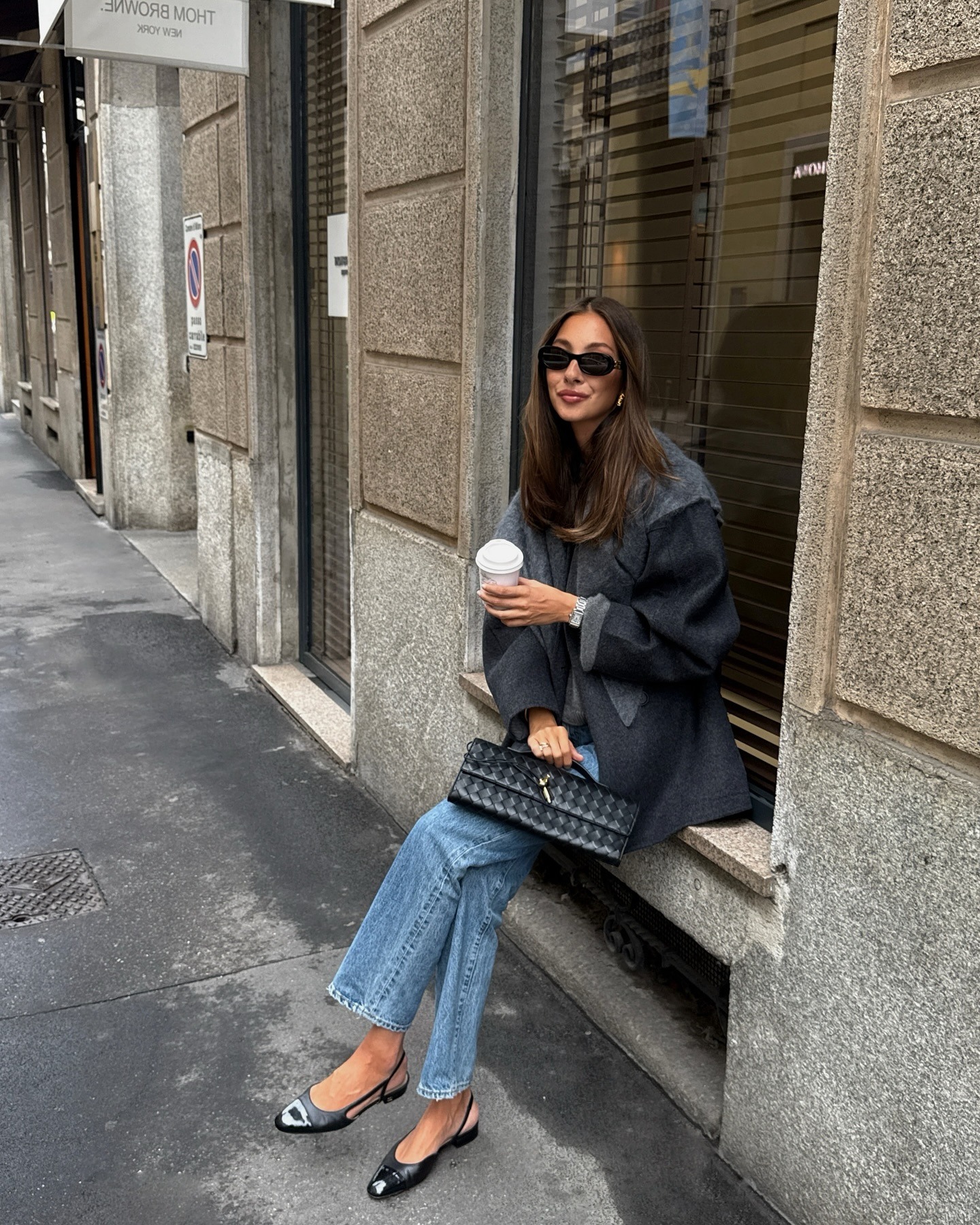 Woman wears grey blazer, blue jeans, slingback pumps and carries bottega veneta andiamo clutch