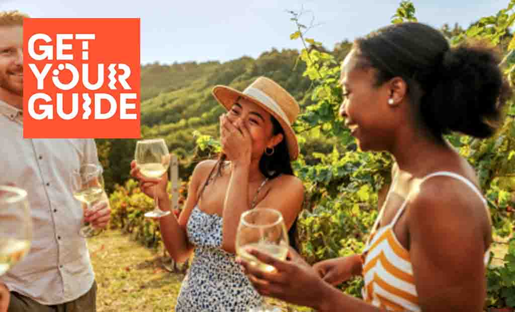 get your guide logo top left with three people laughing in a wine field drinking white wine
