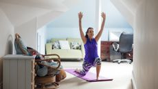 Woman in lunge position with her arms raised overhead in a domestic setting