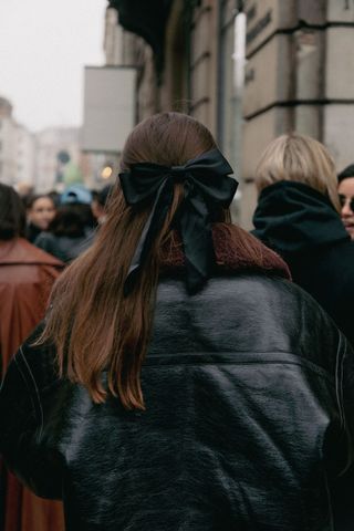 editor Halie LeSavage attends Copenhagen Fashion Week with an oversize black bow clip from Pico Store in her hair