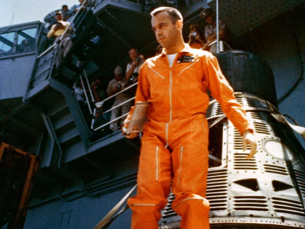 Astronaut Alan B. Shepard Jr. walks away from his Freedom 7 capsule following a post-flight inspection aboard the carrier USS Champlain. Earlier Shepard had completed the historic 15-minute suborbital Mercury-Redstone 3 mission, marking America's inaugural manned trip into space.