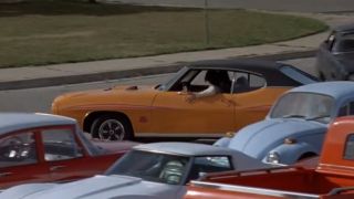 An orange car pulls around a parking in Dazed and Confused.