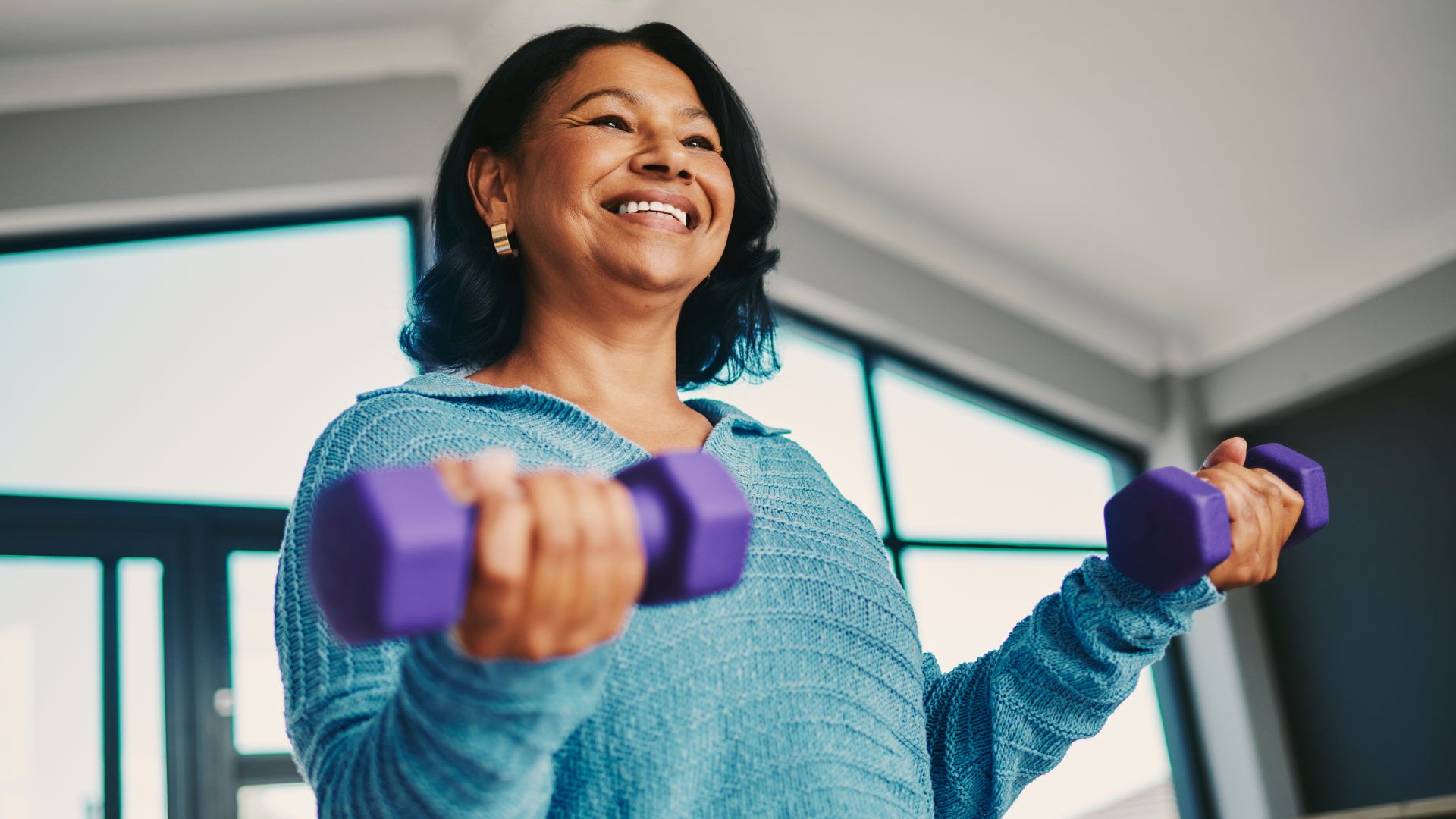 Woman smiling holding dumbbells