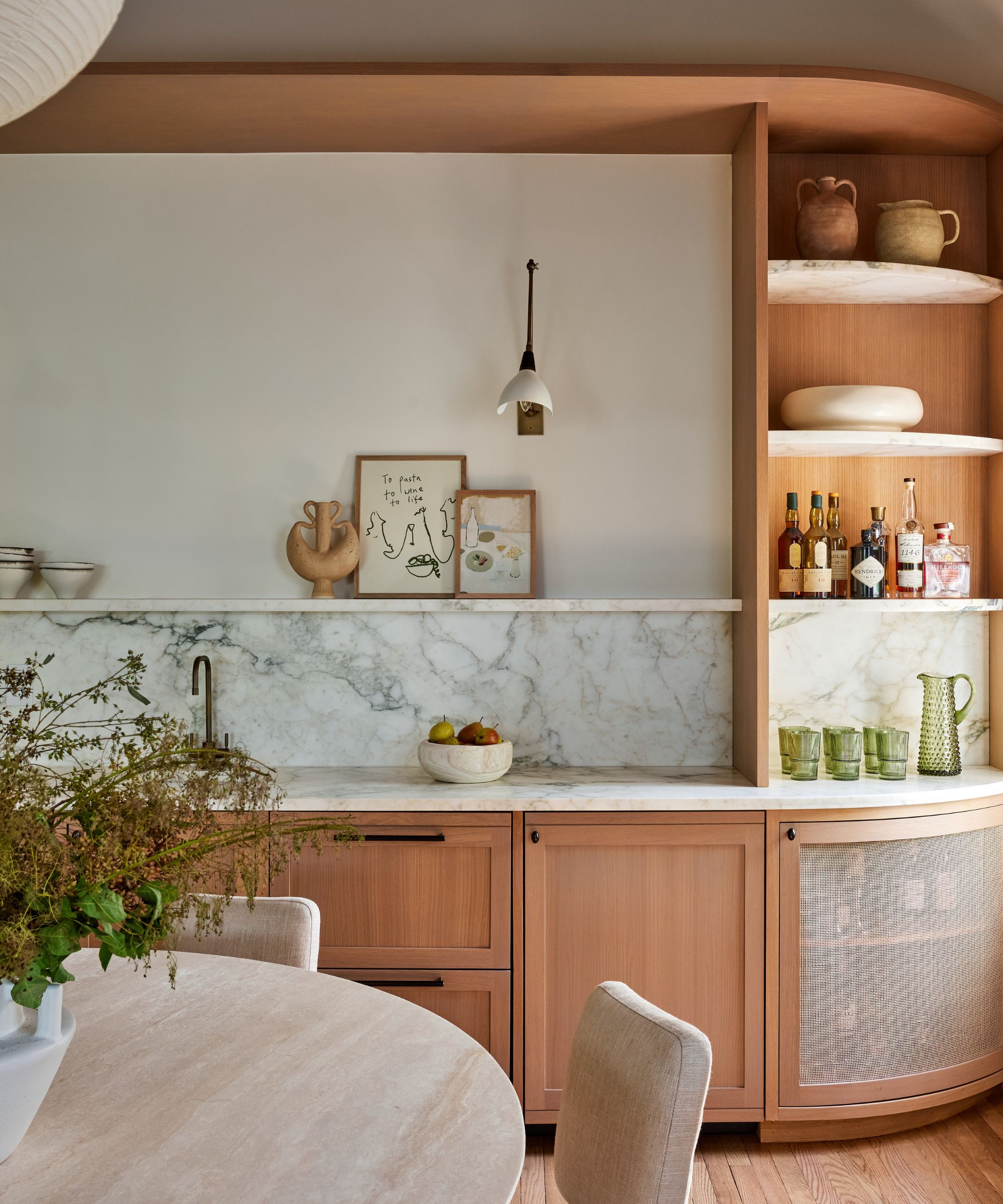 Dining room with marble sink, wood cabinets, open shelves and round table