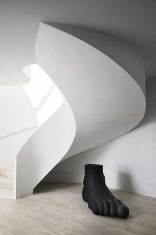 White spiral staircase with black foot statue at the bottom