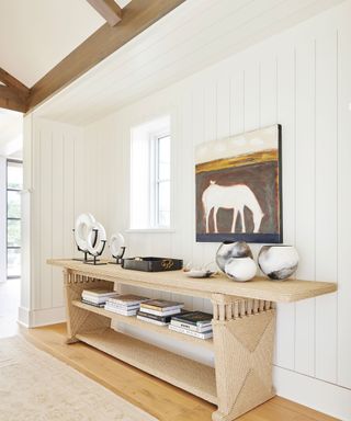 Entryway with console table and decoration, artwork on wall, runner