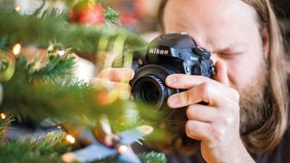 Person holding Nikon D800 with Lensbaby Spark 2.0 attached and pointing it towards a Christmas tree