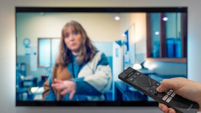 TV remote control being pointed at Philips Ambilight OLED TV