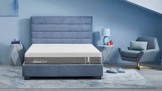 The Tempur-Pedic Cloud Hybrid mattress placed on a blue-gray rug in a blue bedroom
