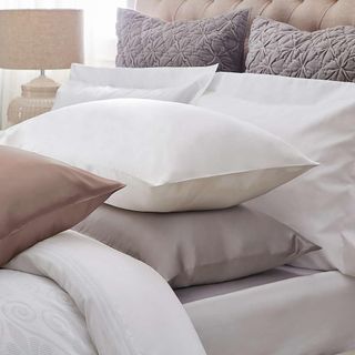 silk pillows with white bedsheet and lamp