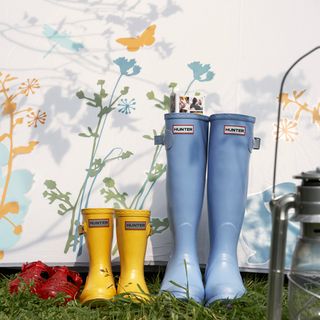 yellow and blue wellies and gardening shoes and white wall