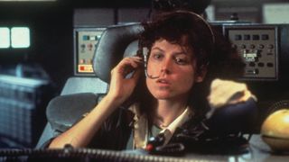 Ellen Ripley is sat in a chair, talking into a headset