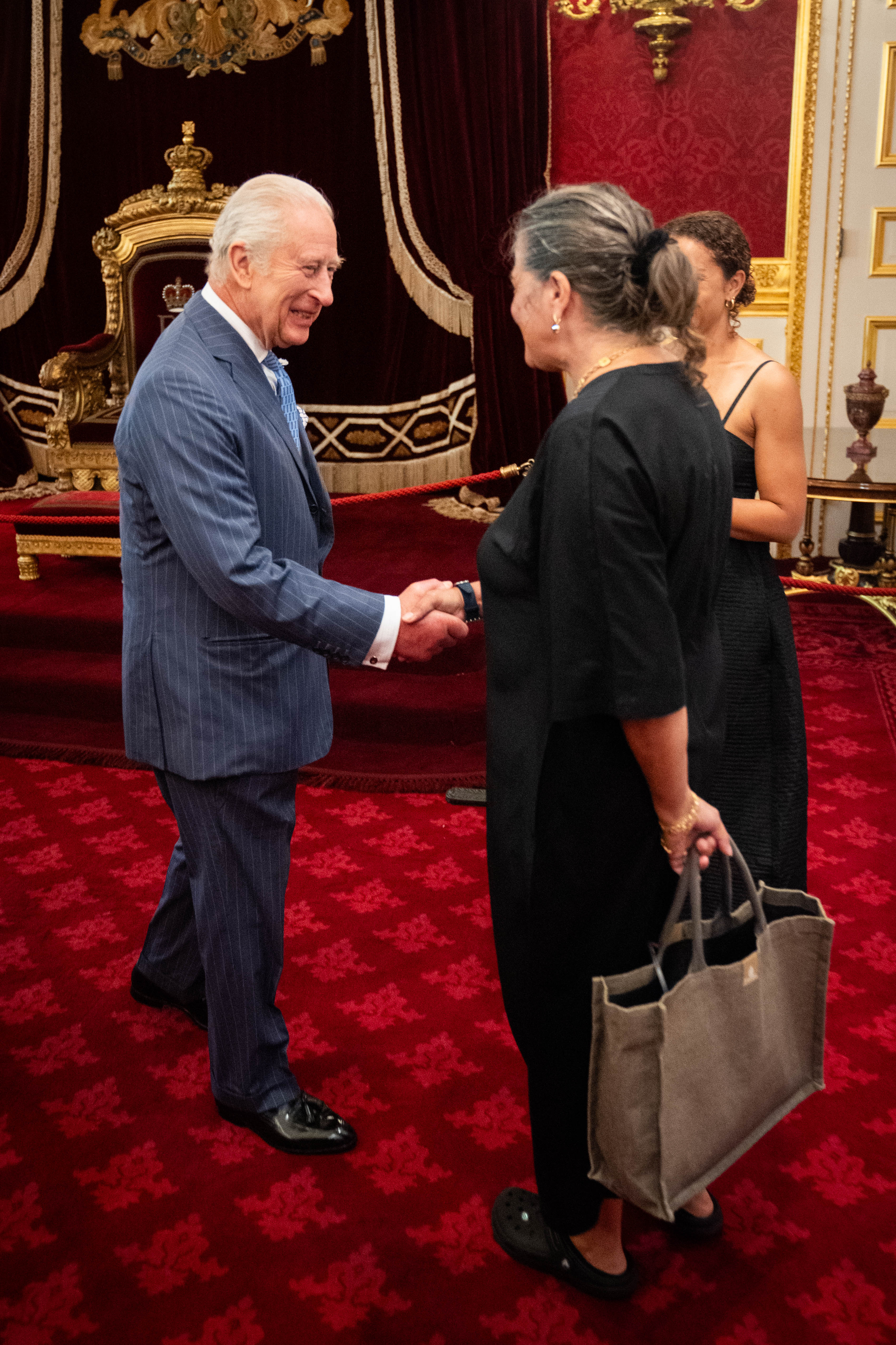 King Charles shaking hands with a woman wearing crocs