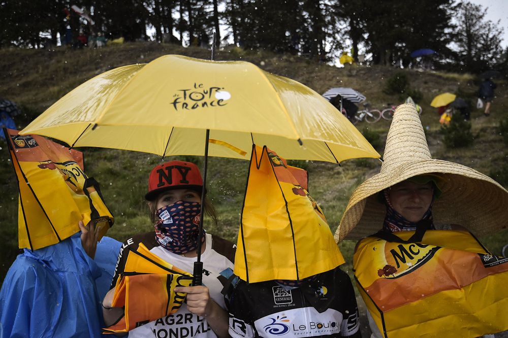 Spectators take cover from the wet weather during stage 12.