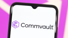 Commvault logo and branding pictured on a smartphone screen, with branding blurred in background.