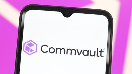 Commvault logo and branding pictured on a smartphone screen, with branding blurred in background.