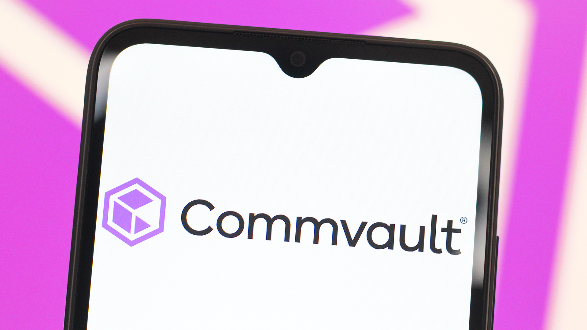 Commvault logo and branding pictured on a smartphone screen, with branding blurred in background.