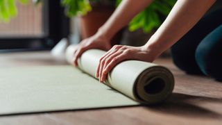 Woman rolling up yoga mat with hands