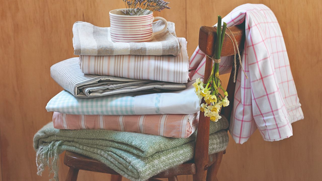 A wooden chair with folded blankets and home linen with flowers