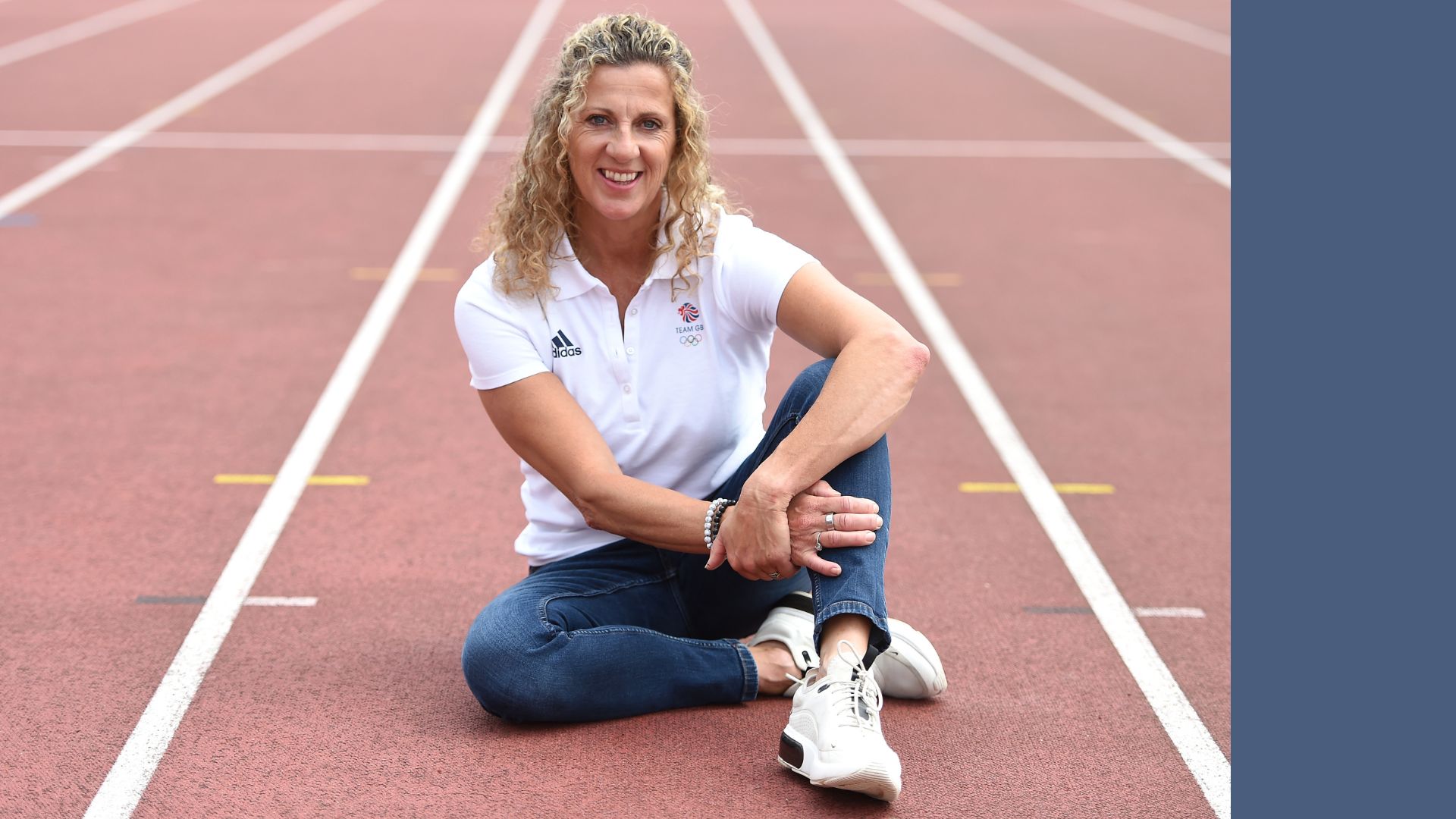 Sally Gunnell sitting on running track, smiling