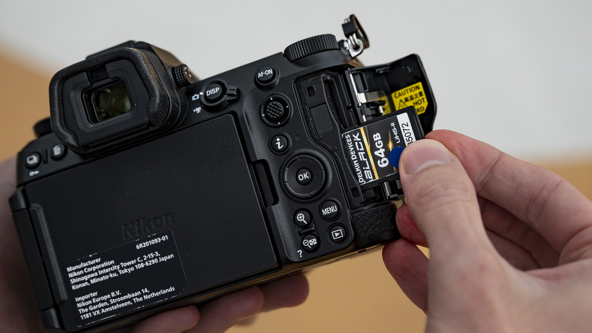 Nikon Z6 III camera in the hand with SD memory card being inserted