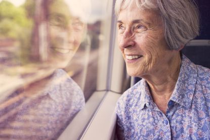 senior woman happily looking out of a train window