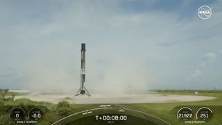 A black and white spacex falcon 9 rocket first stage sits on a landing pad.