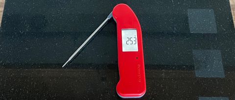 The ThermoWorks Thermapen One open and with the display in portrait mode on a balck granite chopping board