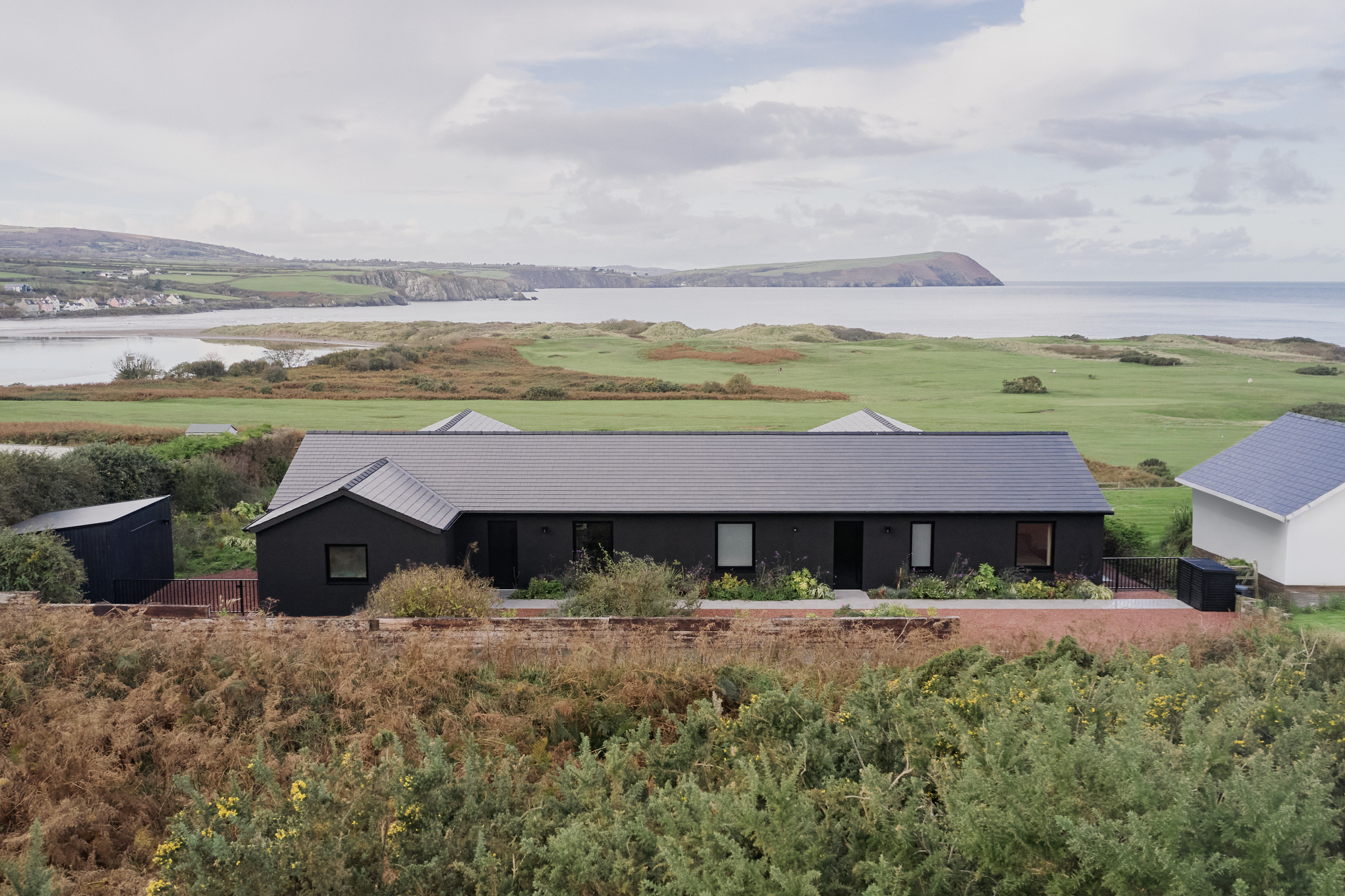 view of a welsh cottage or bungalow type building facing the sea and redesigned in a fairly minimalist, contemporary way
