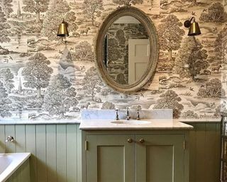 A bathroom with green panelling and monochrome patterned classic wallpaper