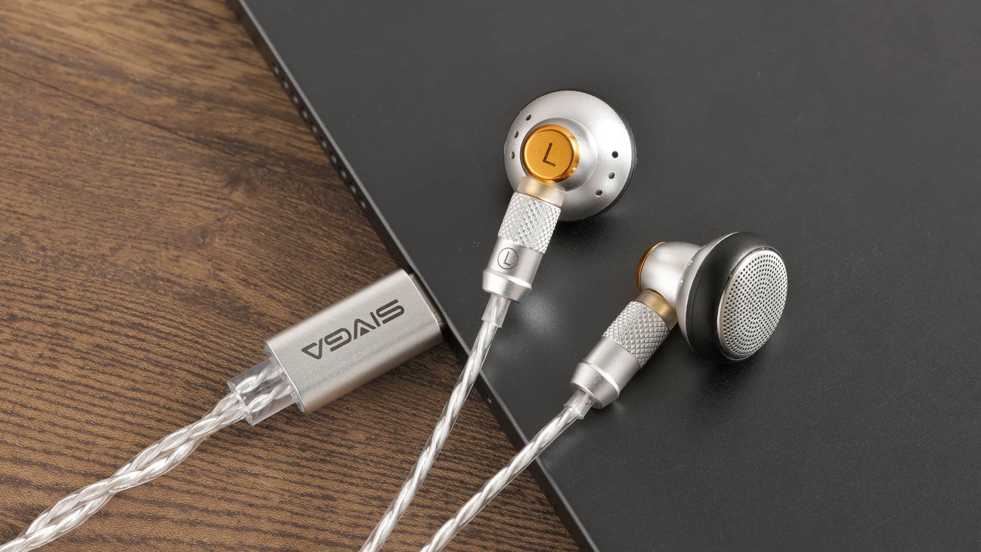Image of the SIVGA M260 earbuds sitting on a wooden gaming desk.