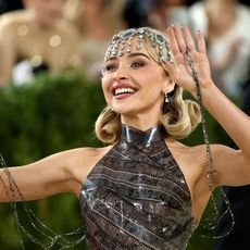 a white woman with blonde hair waves to a crowd on a red carpet