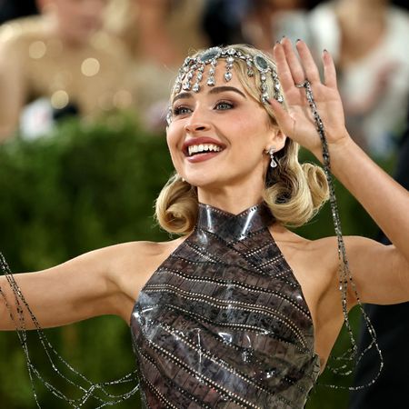 a white woman with blonde hair waves to a crowd on a red carpet