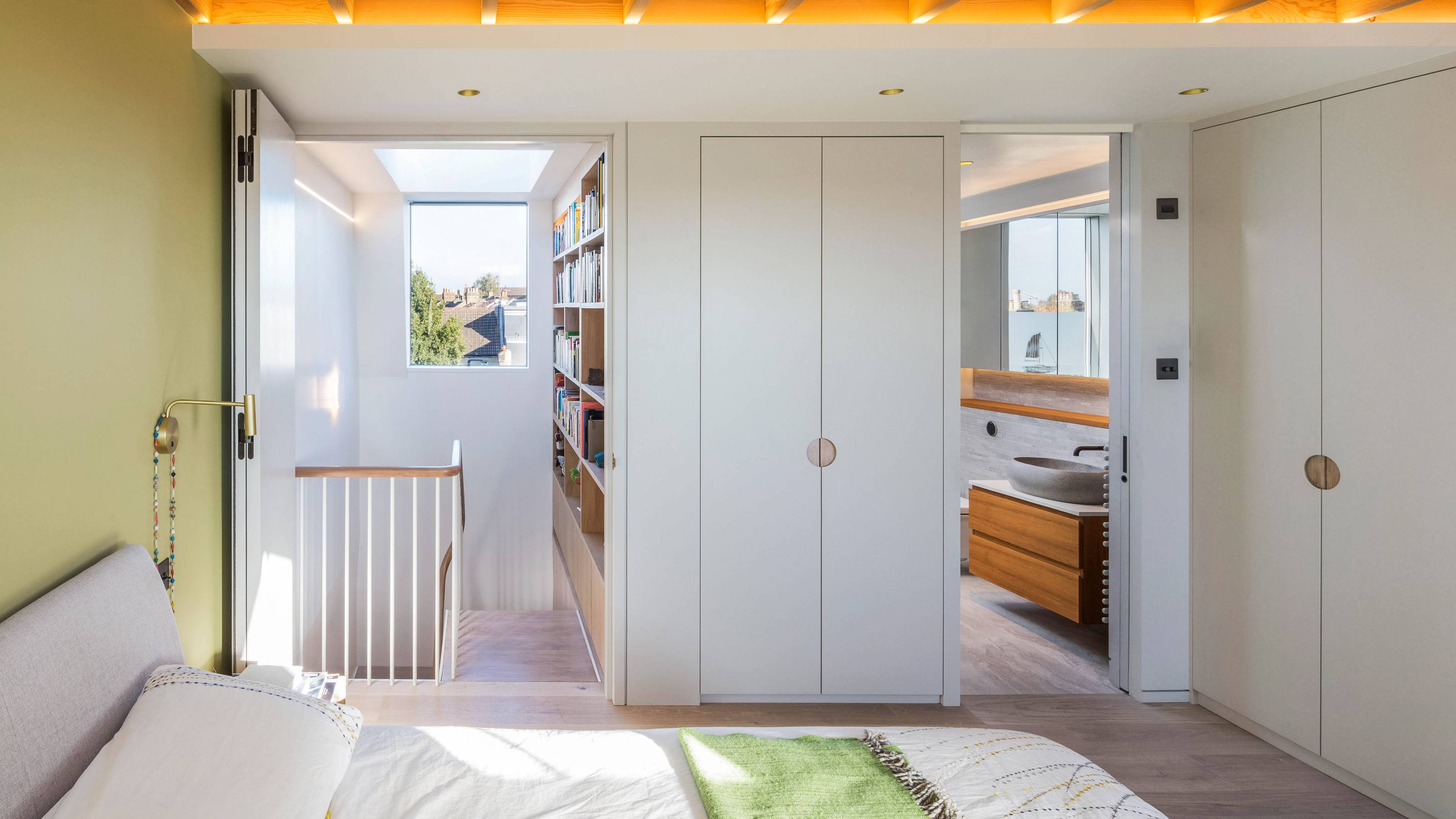 white and green bedroom in loft conversion with staircase and en suite bathroom