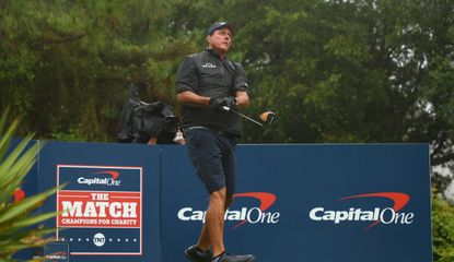 Mickelson hits a driver in front of The Match banners