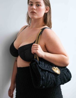 Model in bra holding knitted handbag