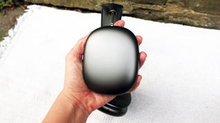 Someone holding the exterior of the Apple AirPods Max earcup against a white surface