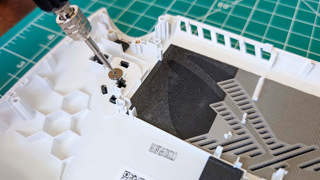 A screwdriver unscrewing the left back button on ROG Ally.