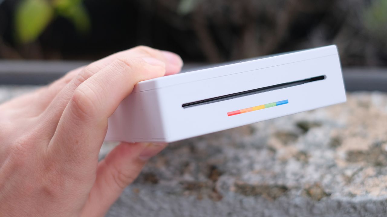 Photograph of Polaroid Hi-Print 3x3 mini instant printer held horizontally with print-output slot visible.