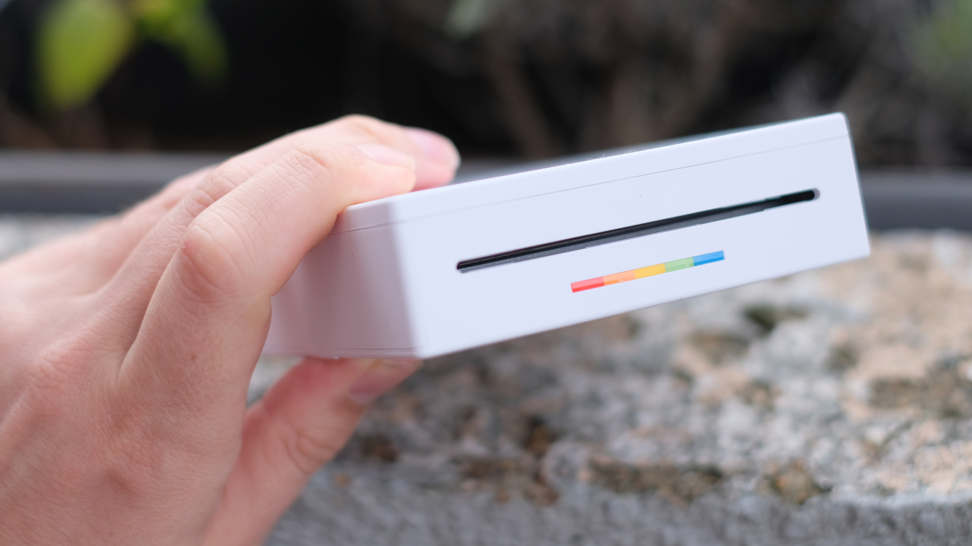 Photograph of Polaroid Hi-Print 3x3 mini instant printer held horizontally with print-output slot visible.