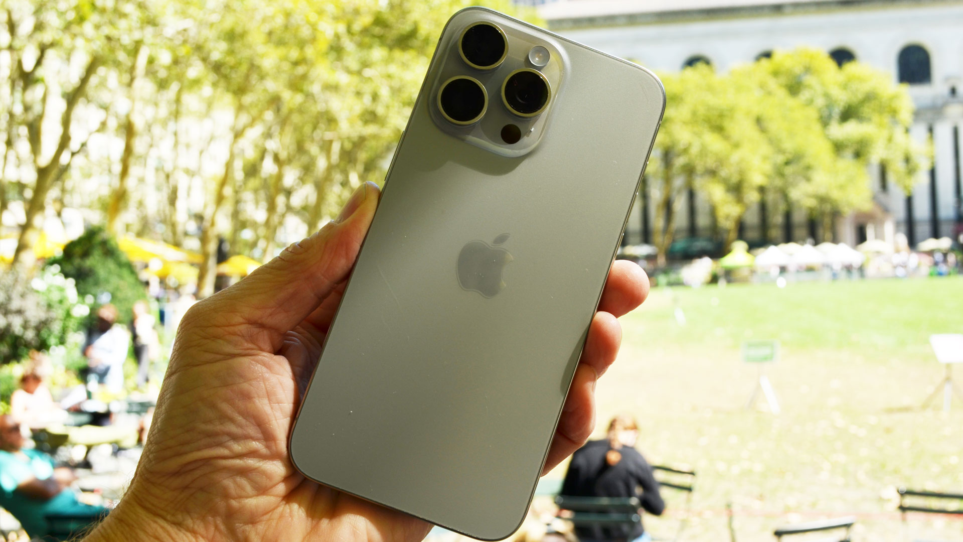 Apple iPhone 15 Pro Max ihmisen kädessä ulkotiloissa
