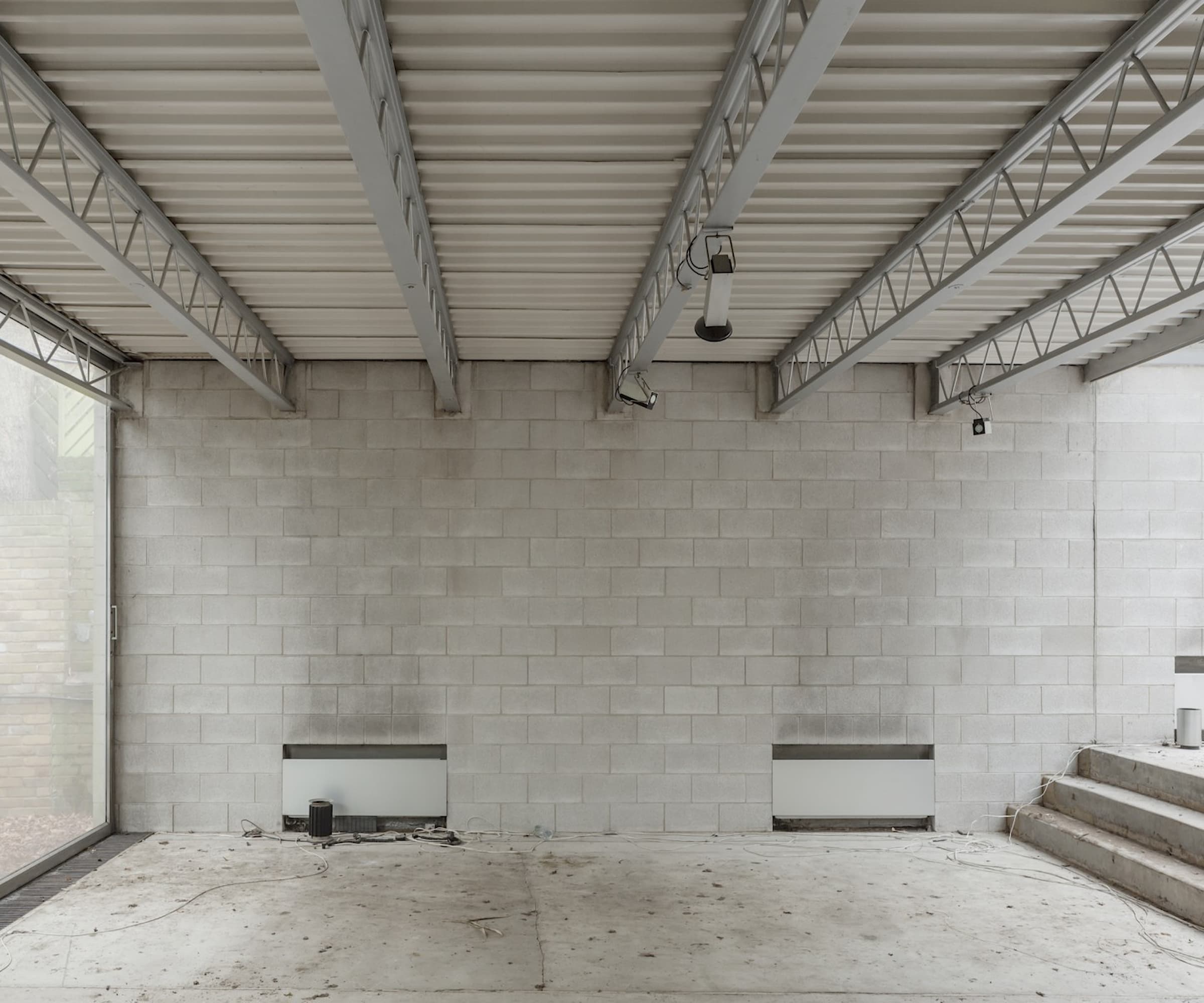 An empty living room with concrete walls and a floor to ceiling window