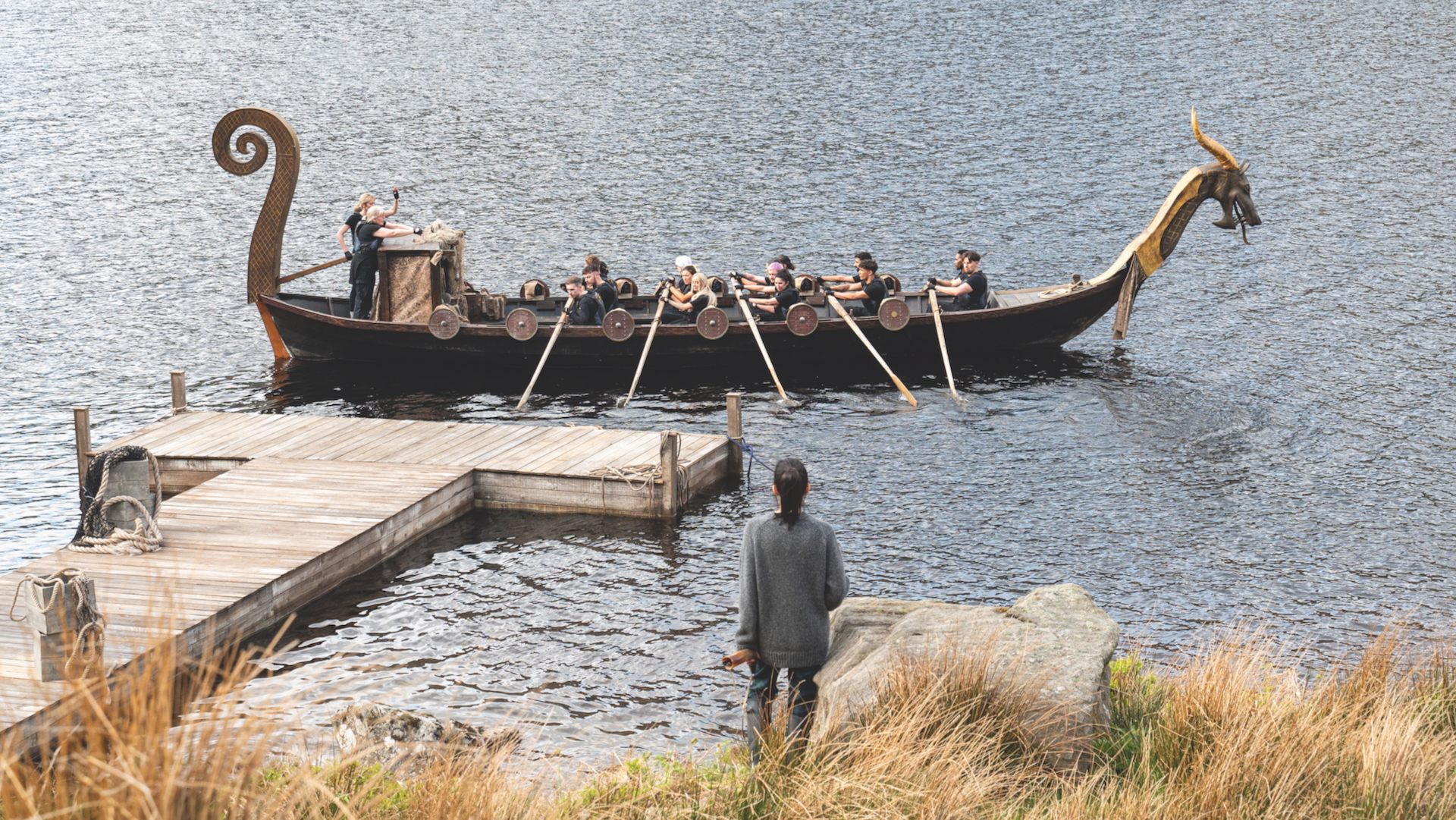 A still from The Traitors shows the contestants rowing a Viking longship
